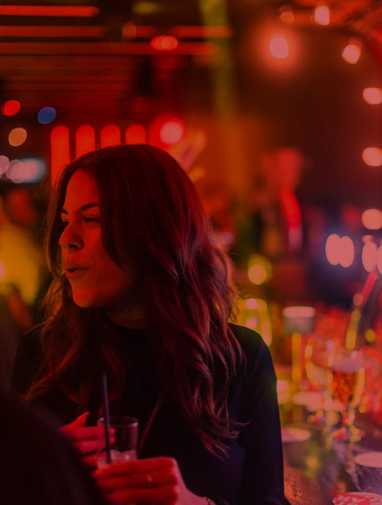 een vrouw die aan de bar staat met een drankje aan de bar