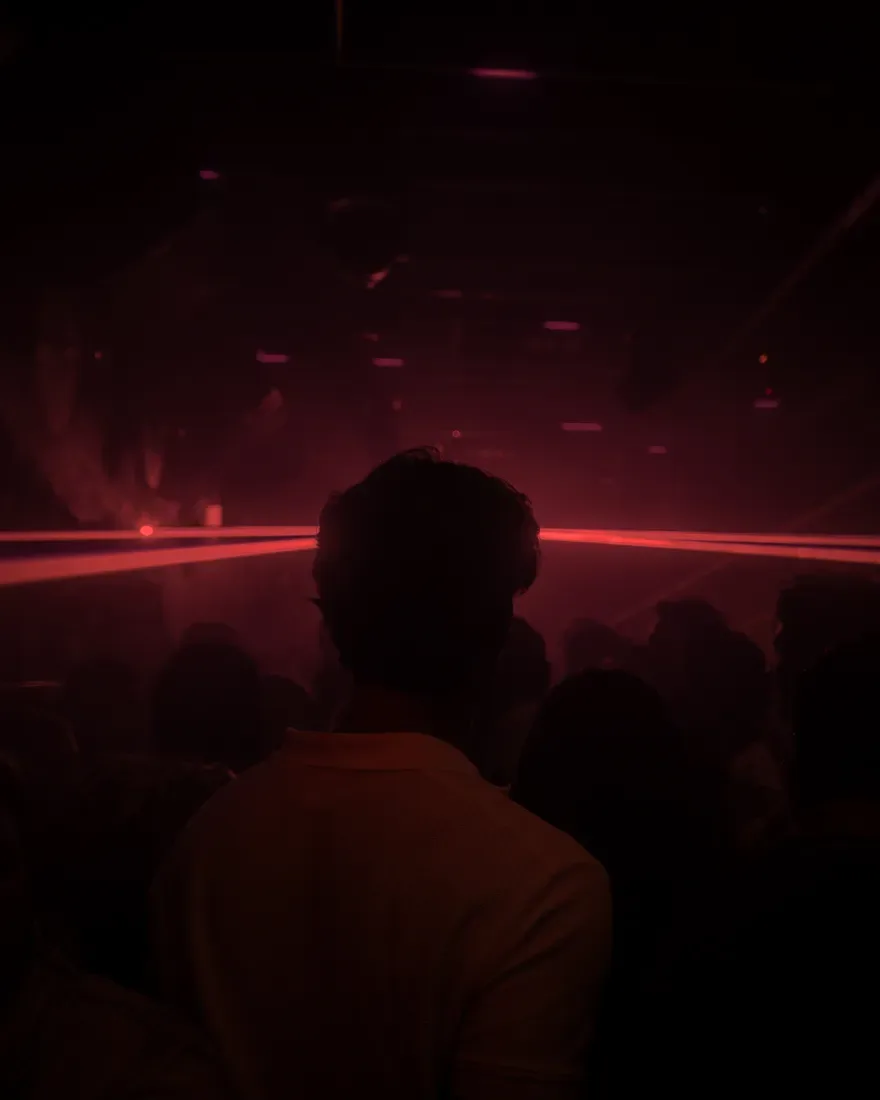 Persoon in een menigte met lasers en dimlicht in een nachtclub